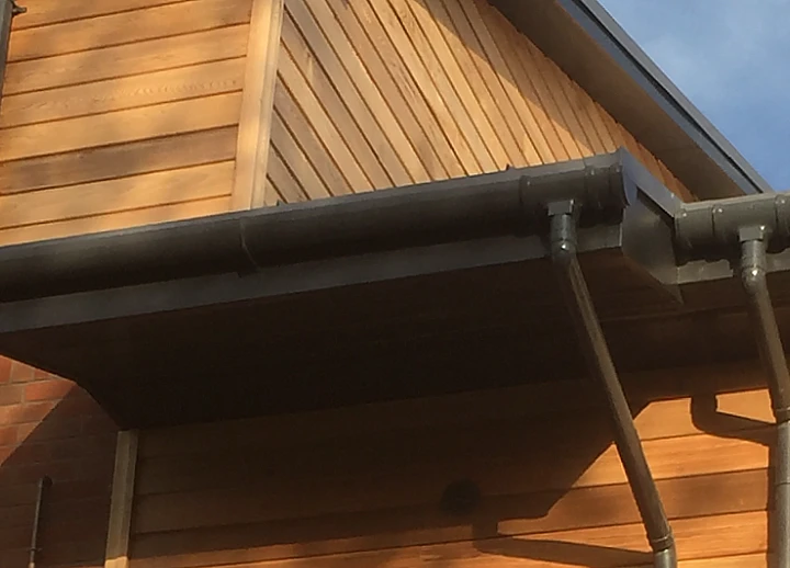 Anthracite grey deep flow high capacity gutter installed with timber cladding.